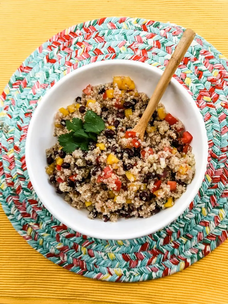 finished mexican quinoa with cilantro and wooden spoon on mat