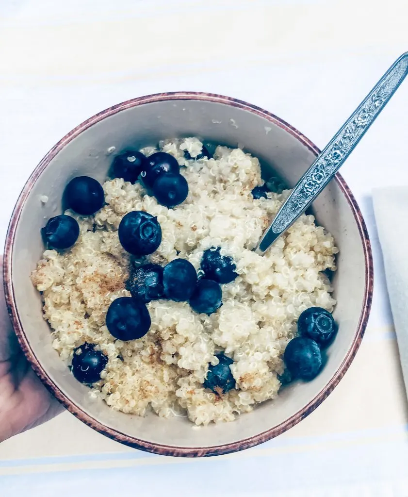 partially eaten bowl of breakfast quinoa held by hand