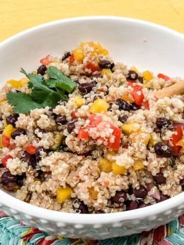 southwestern quinoa salad in white bowl with wooden spoon