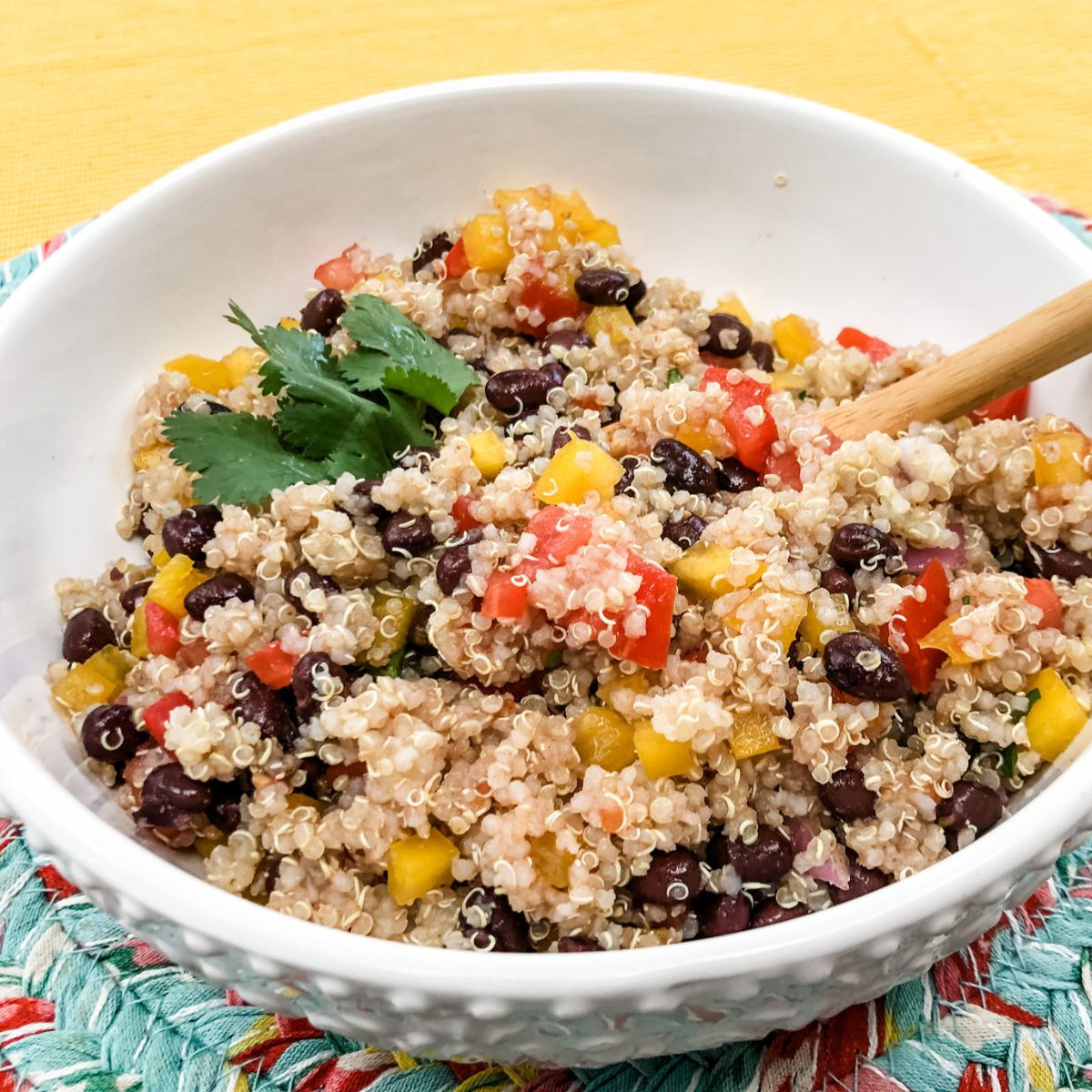 southwestern quinoa salad in white bowl with wooden spoon