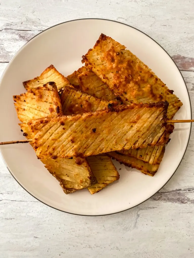 garlic parmesan hasselback waffle potatoes served on white plate
