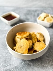 banana pancakes in bowl with banana slices and syrup