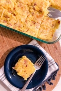 casserole dish of cheddar bacon polenta squares with one square plated