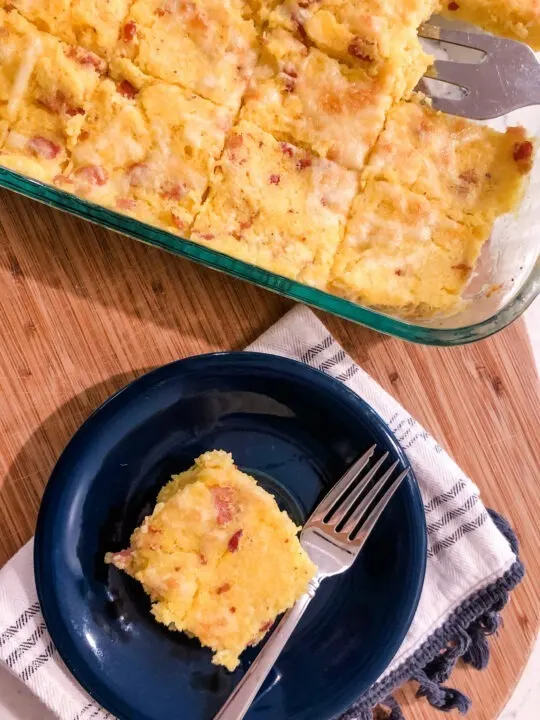 casserole dish of cheddar bacon polenta squares with one square plated