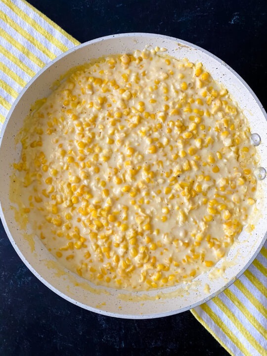 skillet of gluten free southern creamed corn recipe ready to serve with yellow striped towel