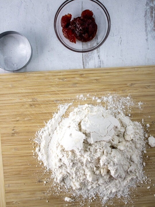 Gluten Free Toaster Pastry Crust Dough on wooden cutting board Before Kneading with strawberry jam in bowl and cookie cutter ring