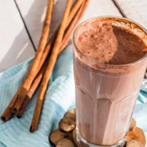 gluten free protein shake with chocolate, banana, peanut butter and cinnamon on blue cloth