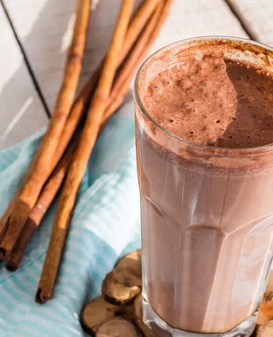 gluten free protein shake with chocolate, banana, peanut butter and cinnamon on blue cloth