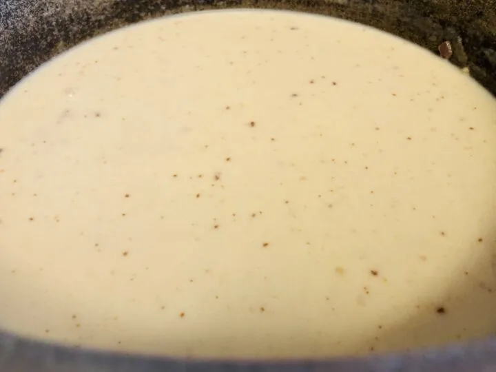 adding milk and broth into the loaded potato soup