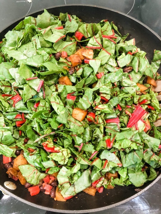 swiss chard leaves added to vegetarian tostada filling with potato and black beans