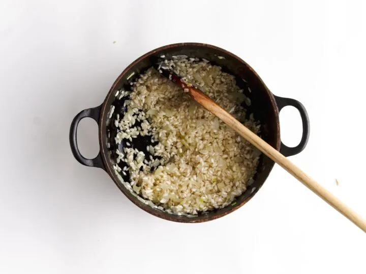 onion garlic and rice in pot with wooden spoon