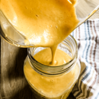 pouring gluten free dairy free cheese sauce from blender pitcher into large mason jar