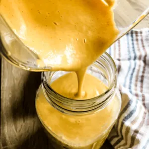 pouring gluten free dairy free cheese sauce from blender pitcher into large mason jar