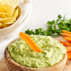 White Bean Green Goddess Dip in wooden bowl with carrots and chips