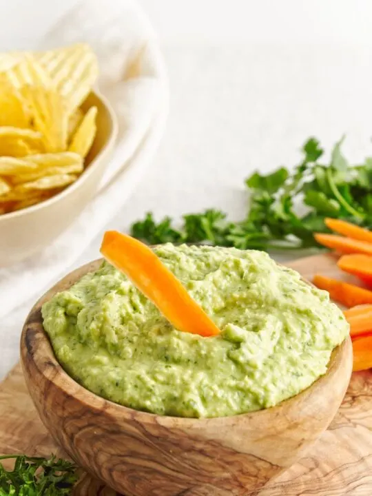 White Bean Green Goddess Dip in wooden bowl with carrots and chips