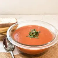 finished tomato soup with grilled cheese on cutting board with spoon