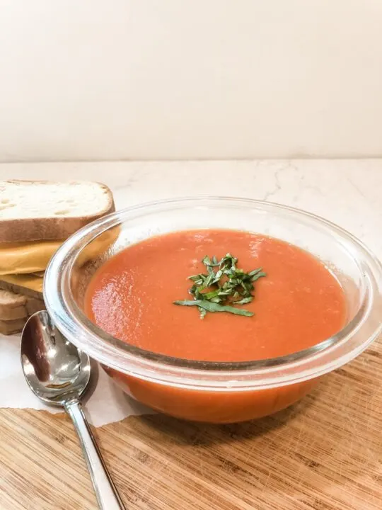 finished tomato soup with grilled cheese on cutting board with spoon