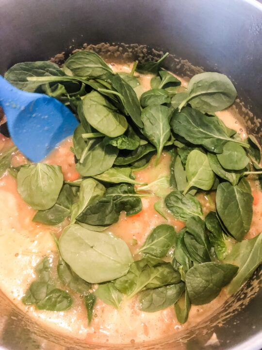 Adding spinach into lemon chickpea soup in pot