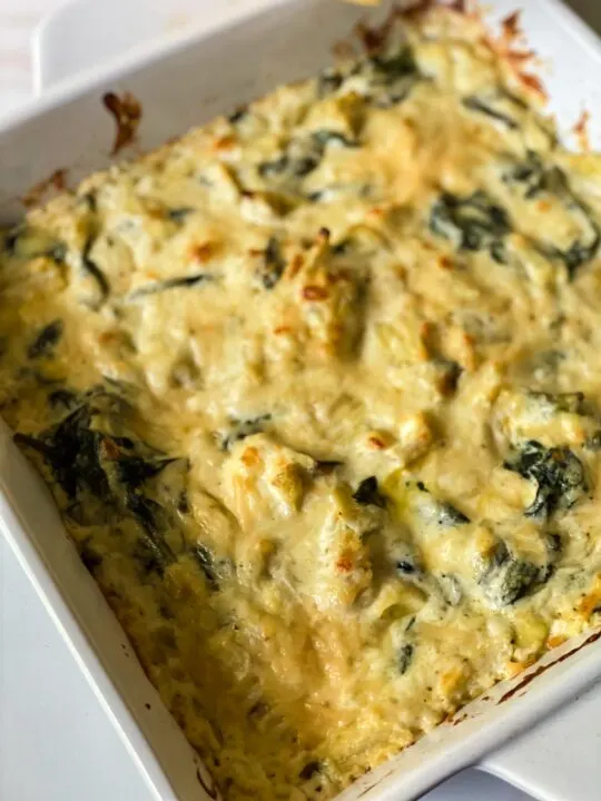 baked spinach artichoke dip coming out of oven in white baking pan