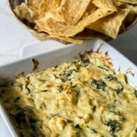 baked spinach artichoke dip out of oven with tortilla chips on marble counter
