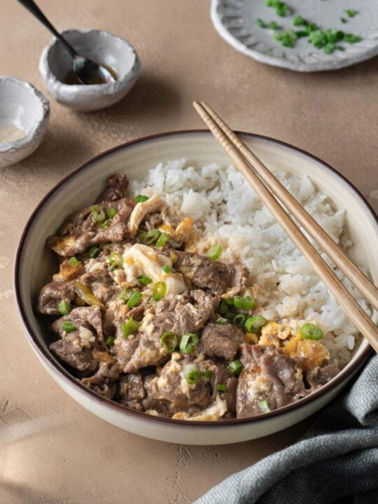 beef and egg over rice in bowl with chopsticks