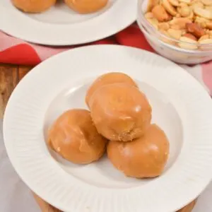 gluten free donut holes on white plates with bowl of peanuts on wooden cutting board
