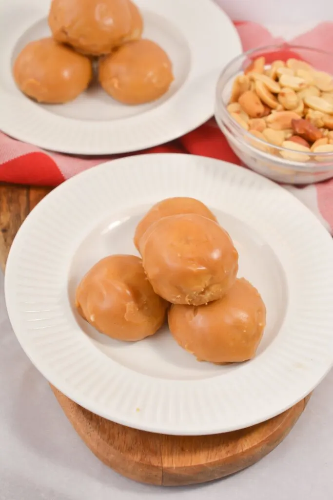 gluten free donut holes on white plates with bowl of peanuts on wooden cutting board