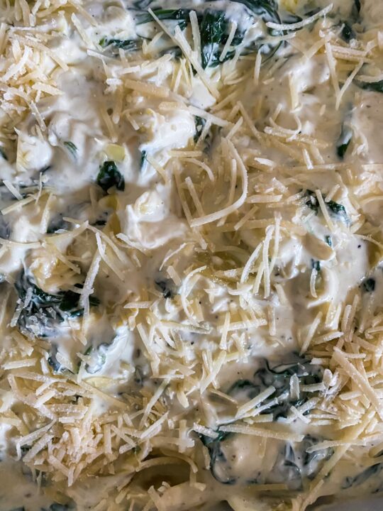topping spinach artichoke dip with shredded cheese before baking
