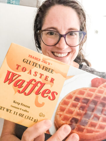 Sharon holding a box of Trader Joe's Gluten Free Toaster Waffles with freezer in background