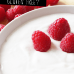 White bowl of white yogurt topped with 3 raspberries, with text overlay that says 'Is yogurt gluten free'