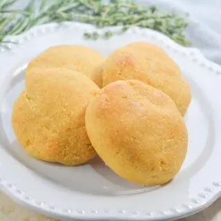 4 gluten free pumpkin bread rolls on a white plate with thyme and gray napkin