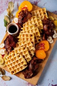 waffle charcuterie board with gluten free dairy free waffles, fruit, bacon, and syrup