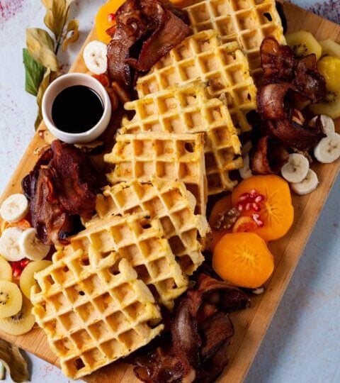 waffle charcuterie board with gluten free dairy free waffles, fruit, bacon, and syrup