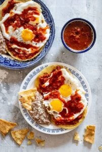 huevos rancheros on plate with beans and corn chips