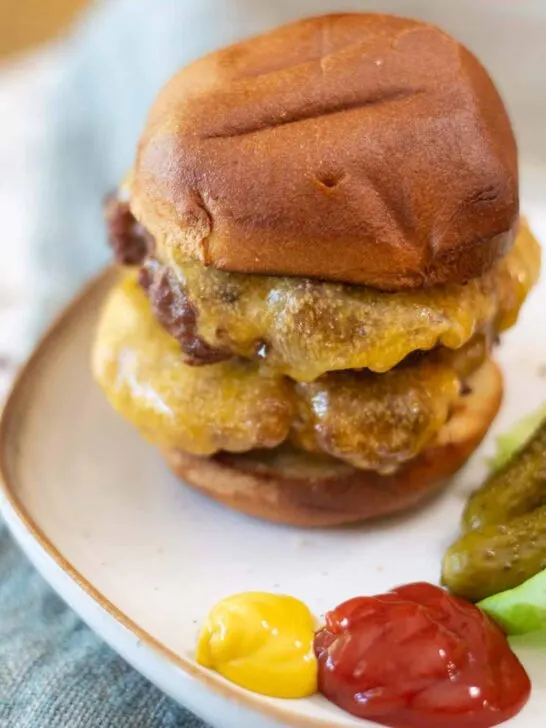 gluten free double cheeseburger on bun with mustard ketchup and pickles