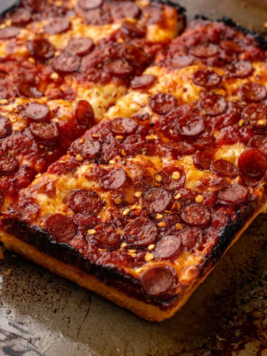 gluten free detroit style deep dish pizza topped with pepperoni and red pepper flakes on baking sheet