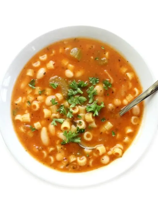 gluten free pasta e fagioli in white bowl with metal spoon