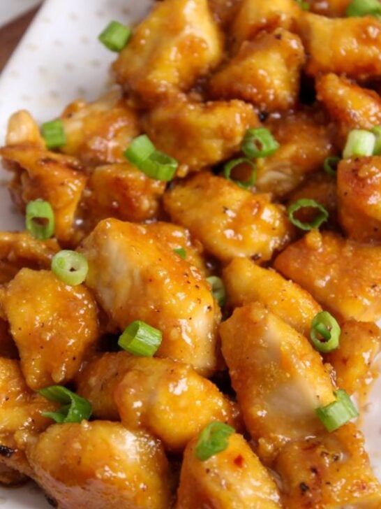 gluten free orange chicken topped with green onions on plate