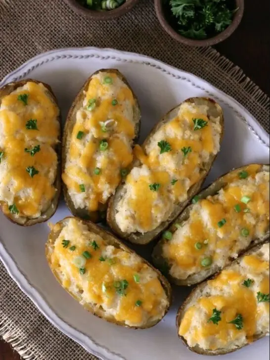 gluten free twice baked potatoes on white plate with herbs in bowls