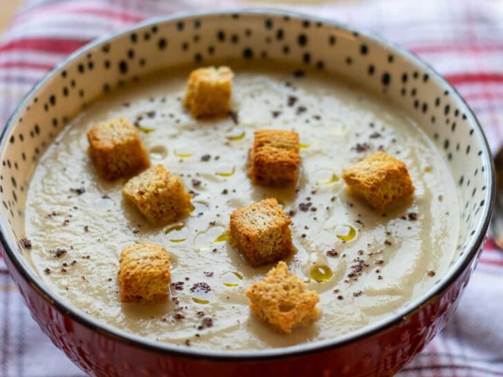 roasted cauliflower soup with celeriac in speckled bowl topped with gluten free croutons