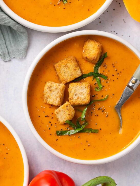 roasted red pepper and squash soup in white bowl with gluten free croutons