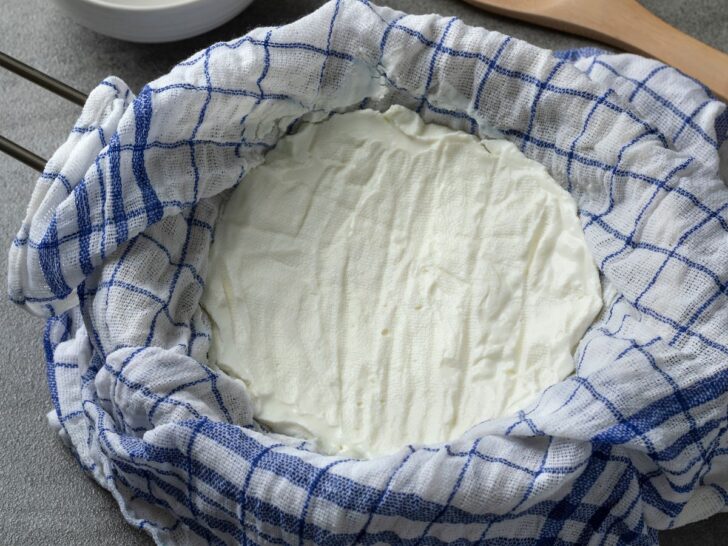 Greek yogurt in cheesecloth on metal strainer