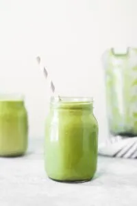avocado and moringa green smoothie in mason jar with striped straw
