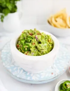 small white bowl of veggie guacamole on light blue plate