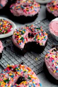 gluten free chocolate donuts topped with pink frosting and sprinkles