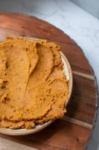 plant based carrot dip in clay bowl on top of a wooden board