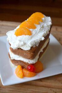tres leches cake stacked with whipped frosting and mandarin orange slices