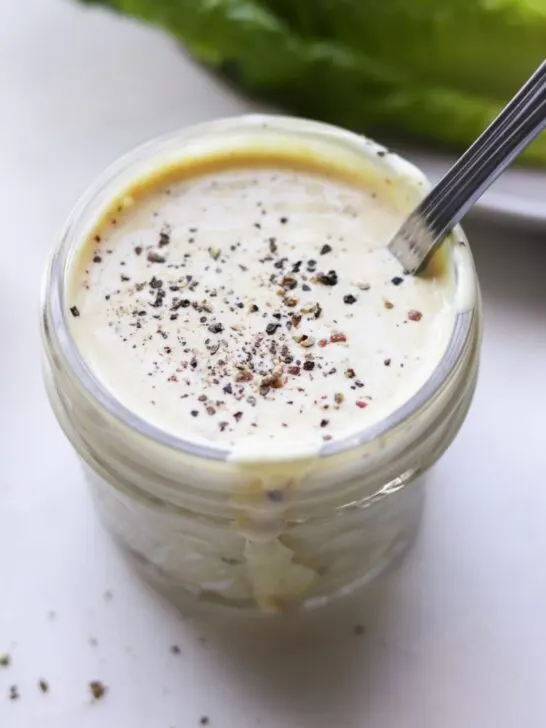 Whole30 Caesar Salad Dressing in jar with spoon and cracked pepper