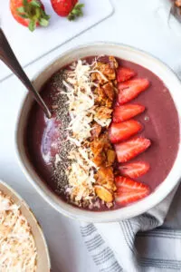acai bowl superfood breakfast topped with strawberries, walnuts, coconut, and chia seeds