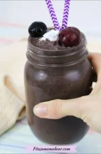 chocolate cherry protein shake in a mason jar with purple straw